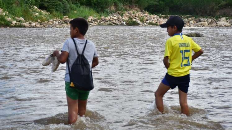 A diario, adultos y niños atraviesan el río para cumplir sus obligaciones.